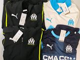 three men ' s soccer shirts and pants sitting on a table