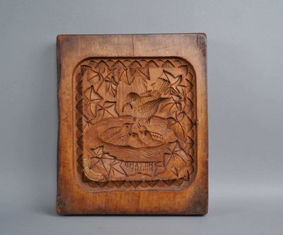 wooden carving of a bird in a tree surrounded by leaves