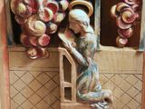 a statue of a woman sitting on a chair in front of a window