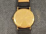 a close up of a wrist watch with a gold coin on it
