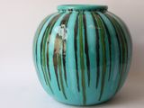 a blue vase with green stripes sitting on a white surface