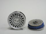 two different types of fly fishing reels on a white surface
