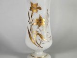 vase doré et blanc orné de fleurs sur un fond blanc