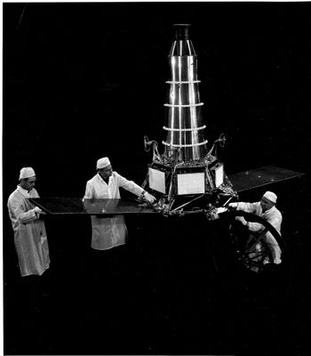 photographie en noir et blanc représentant un groupe d'hommes travaillant sur une maquette de station spatiale