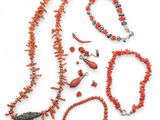 an assortment of coral necklaces and bracelets on a white surface