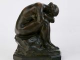 statue of a man sitting on a rock with his head in his hands