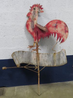 a metal rooster on top of a sign on the side of a building