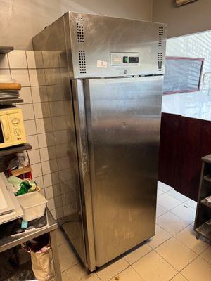 stainless steel refrigerator in a kitchen next to a stove and shelves