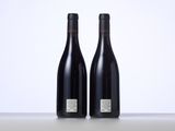 two bottles of wine sitting on top of a table next to each other