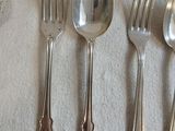 quatre cuillères en argent et deux cuillères en argent posées sur une nappe blanche