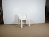 a white chair sitting in front of a white wall