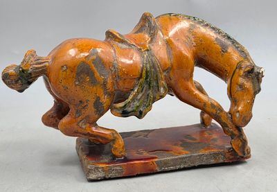 une statue orange et noire représentant un cheval avec un cavalier sur le dos