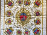 a white and gold scarf with a picture of a coat of arms