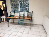 un homme debout dans une pièce où se trouvent une table et des chaises