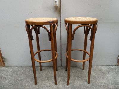 deux tabourets en bois placés l'un à côté de l'autre sur un sol en béton