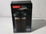 packaging of a coffee maker with two cups of coffee in front of it