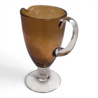 a brown glass cup with a handle on a white plate