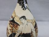 a black and white vase with a picture of a man sitting on a bench
