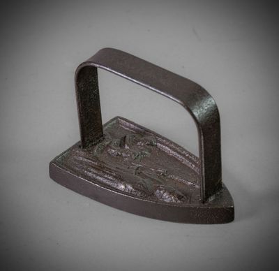 un petit fer à repasser muni d'un manche, posé sur une table