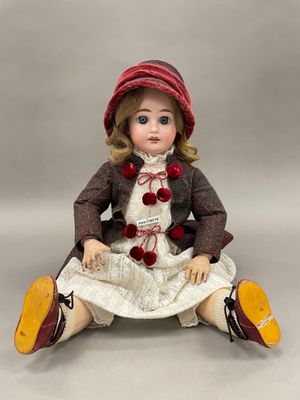 une image représentant une poupée assise par terre, vêtue d'une robe et d'un chapeau