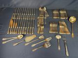 a lot of silverware on a table with a blue cloth
