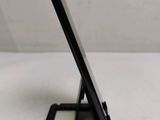 a black cell phone sitting on a stand on a table