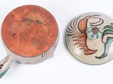 pair of ceramic pots with designs on them on a white surface