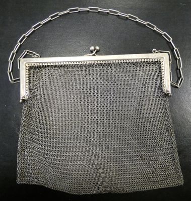 an old silver mesh purse on a table with a chain around it