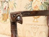 a close up of a wooden chair with a bird head on it