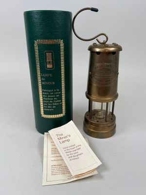 une lampe à huile ancienne en laiton, avec un étui vert et une étiquette