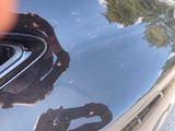 a reflection of a man in a car ' s hood