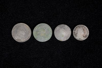 three silver coins sitting on top of a black surface
