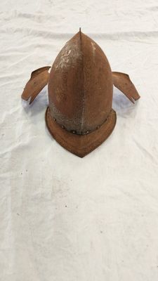 un casque marron posé sur un drap blanc sur un lit