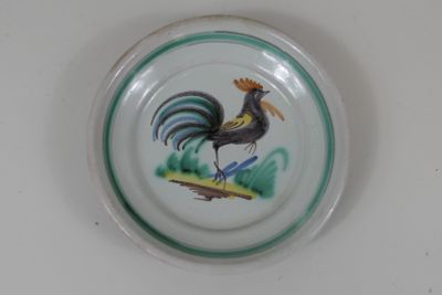 une assiette sur laquelle est peint un coq, posée sur une table