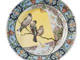 une assiette décorée d'oiseaux, posée sur un socle