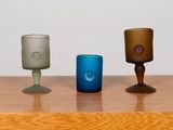 three different colored glasses sitting on a wooden table