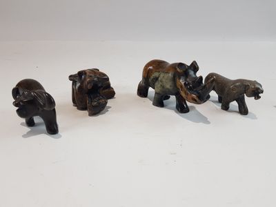 quatre petites figurines d'éléphants posées sur une surface blanche