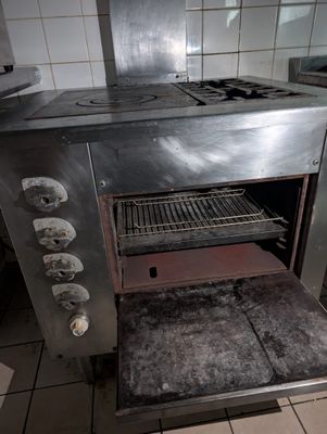 une vieille cuisinière dans une cuisine sale, avec beaucoup de feux