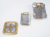 three pieces of silver and gold on a white surface