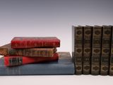 several old books stacked on top of each other on a white surface
