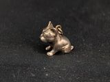 a small silver dog charm sitting on top of a black cloth