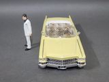 a toy man standing next to a yellow toy car