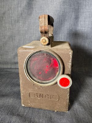 an old red stop light sitting on top of a wooden block
