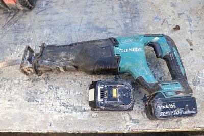 a corded drill and two batteries on a table