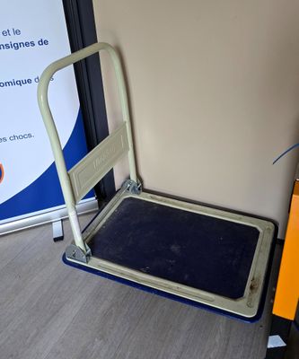 un chariot à bagages posé à côté d'un panneau posé par terre