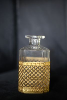 une bouteille en verre avec un bouchon doré posée sur une surface noire