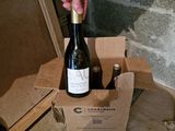 a person holding a bottle of wine in a cardboard box
