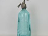 a blue glass bottle with a metal handle on a white surface