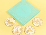 three coasters with a blue box and four coasters with gold designs on them