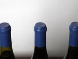 three bottles of wine are lined up on a wooden table